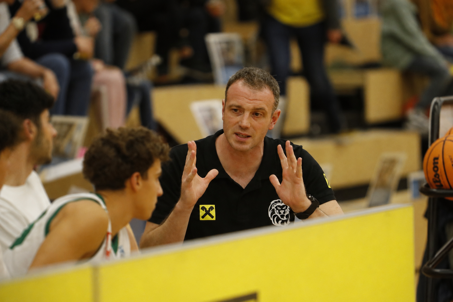 A coach speaking with players on the bench during a game